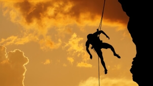 Sil­hou­et­te of a clim­ber on a ver­ti­cal wall over beau­ti­ful sunset